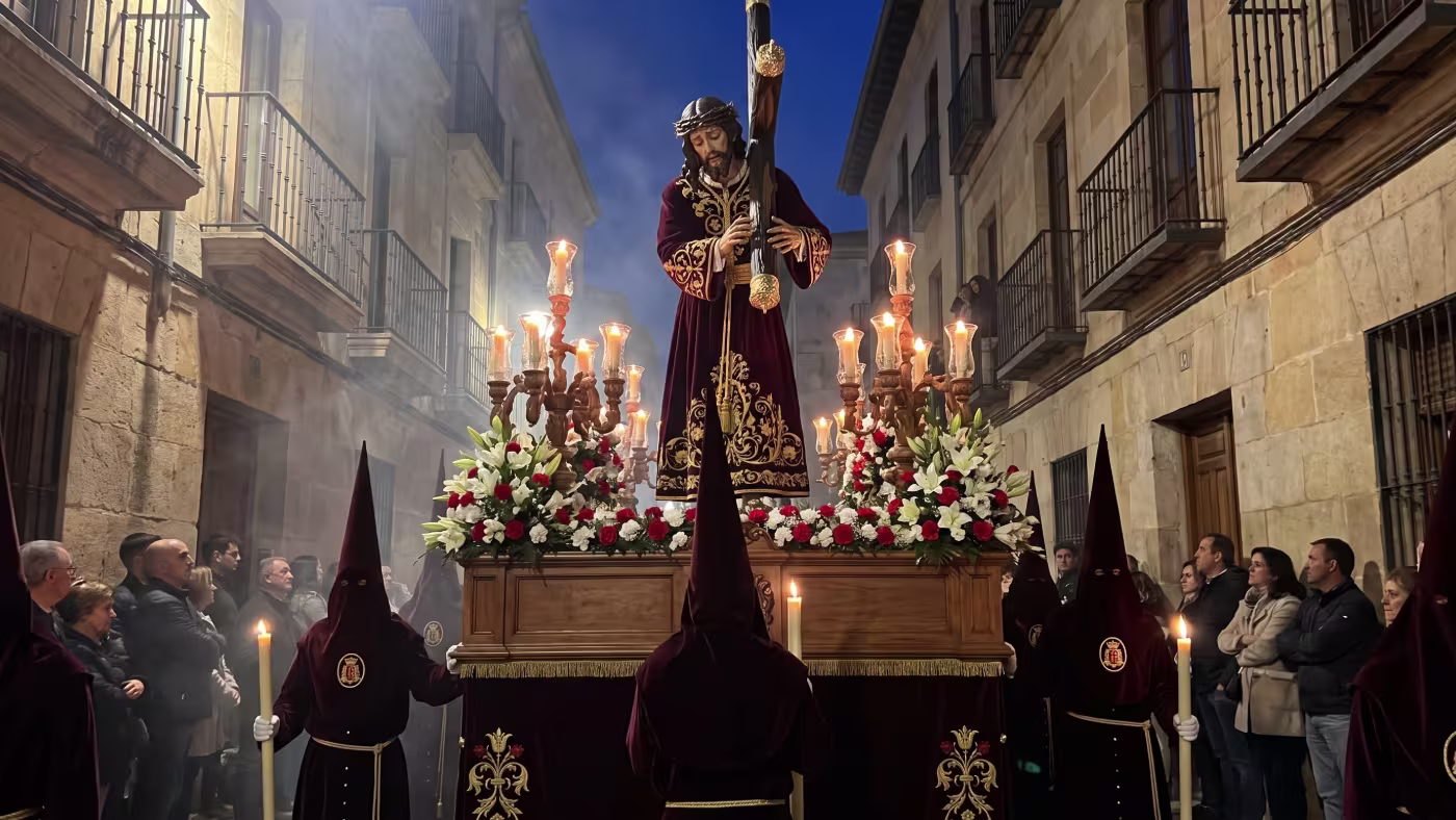 Imagen de Cristo Nazareno a tamaño natural sobre su paso, portada por cofrades durante una procesión nocturna